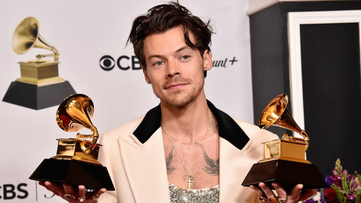 Harry Styles holding two Grammy awards, highlighting his impressive speed in Berlin Marathon under a fake name.