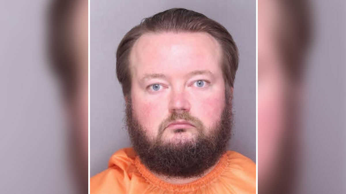 Mugshot of a man in an orange jumpsuit, related to teacher arrested for using p**p spray around school.