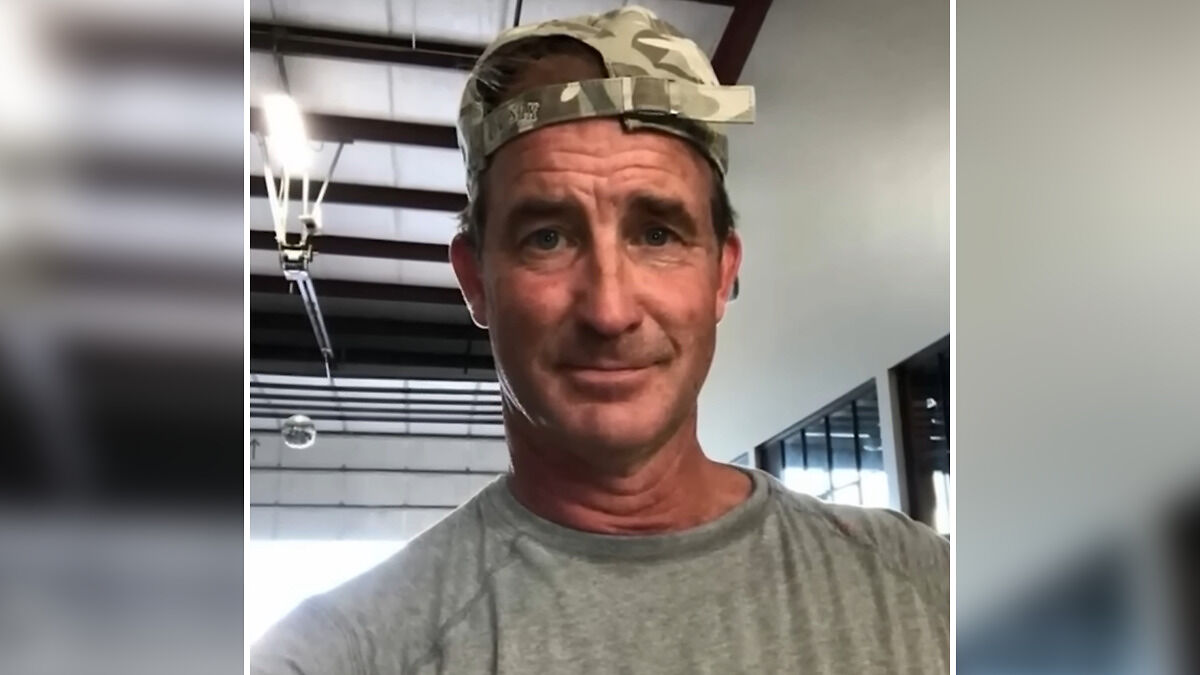 Man in a gray shirt and camo cap indoors, linked to Coldplay KissCam saga involving HR execu2019s husband at concert.