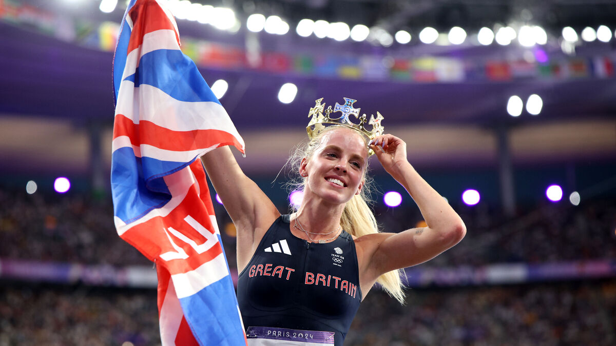 Olympic gold medalist Keely Hodgkinson celebrating victory holding British flag and wearing a crown in stadium.
