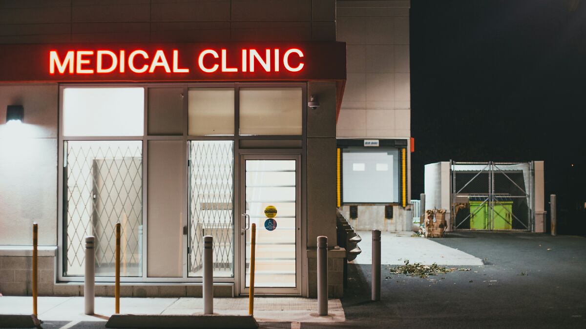 Exterior of a medical clinic at night with a red illuminated sign, related to breast enlargement surgery SEO keywords.