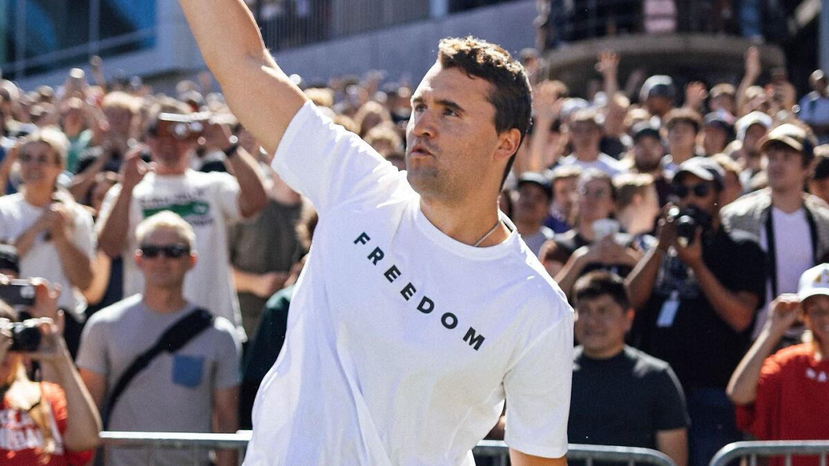 Man in a white freedom shirt raising his arm in front of a crowd, related to TikToker Hannah Brown follower loss controversy.