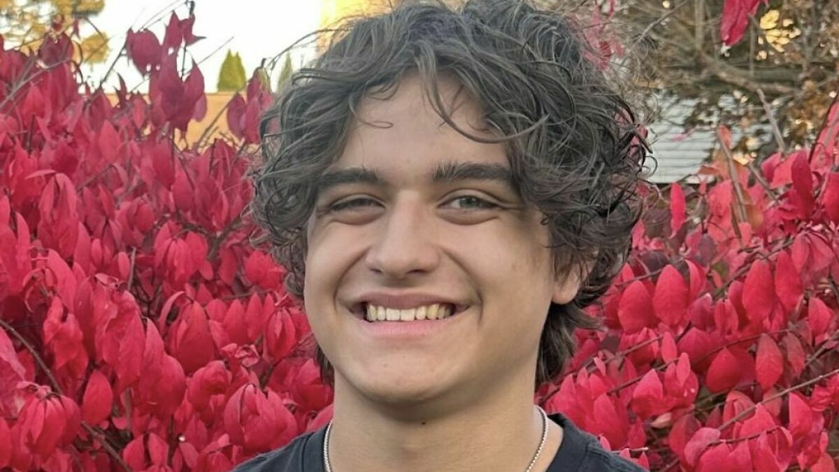 Teenage boy smiling outdoors with red autumn leaves in the background referencing viral TikTok trend injuries.