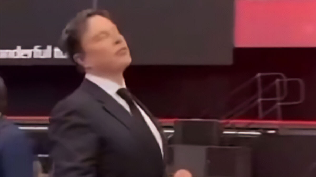 Elon Musk in a black suit and tie at a formal event, surrounded by dark and red background elements.