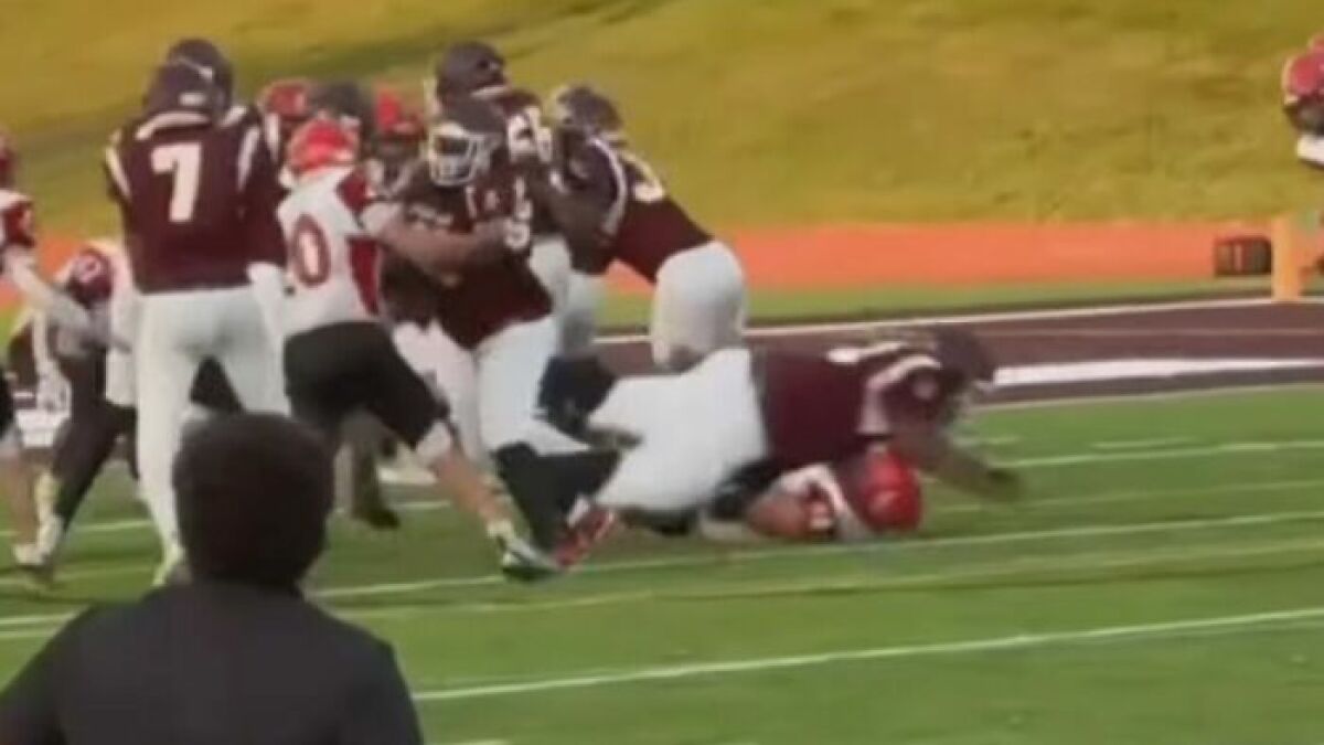 Teen footballer tackling rival on the field during a game, highlighting an intense moment in the match.
