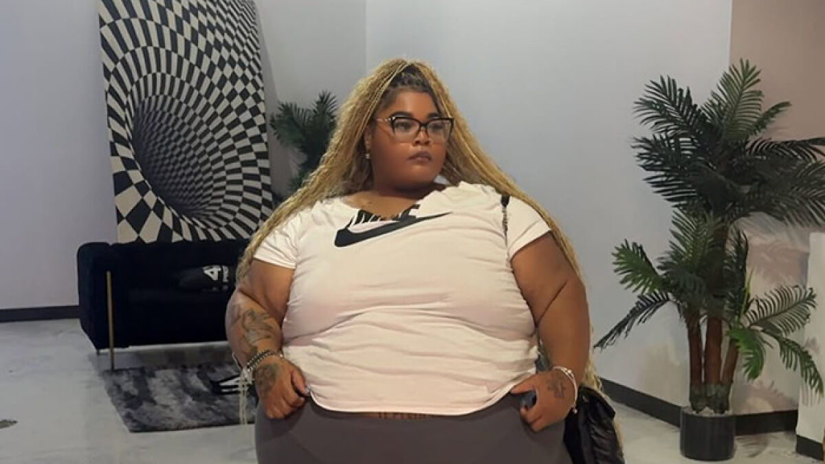 Plus-size woman with long blonde hair and glasses sitting indoors, representing Lyft driver weight discrimination and lawsuit settlement.