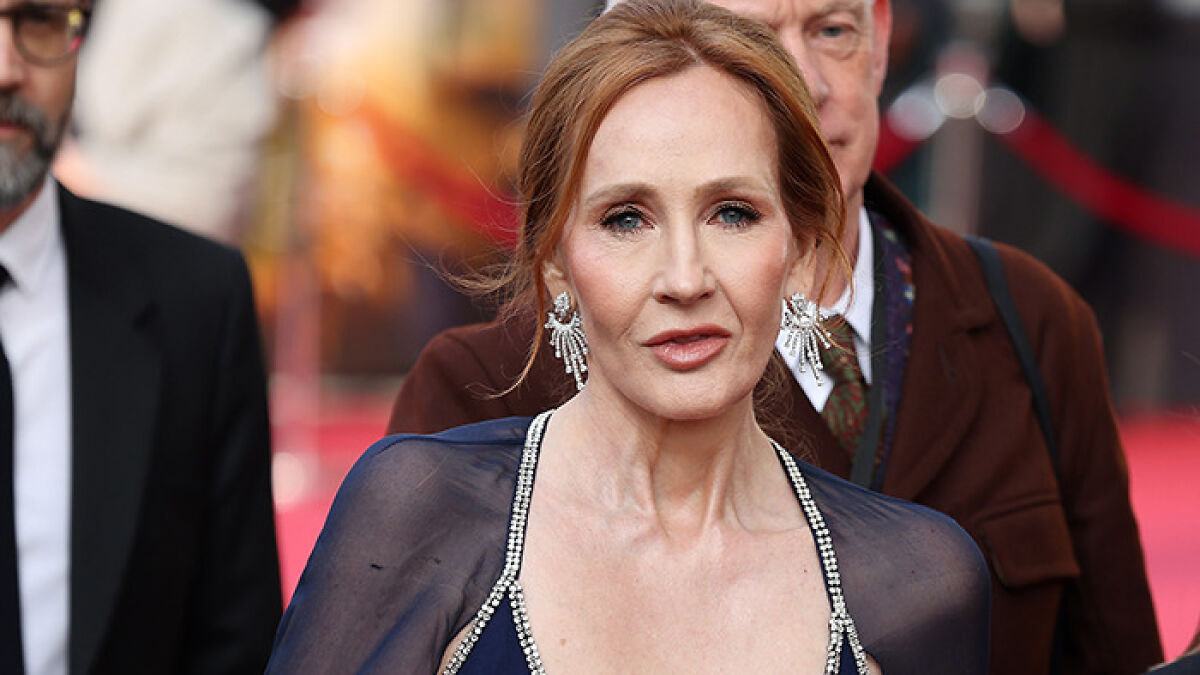 JK Rowling attending an event, wearing a navy dress and statement earrings, sparking renewed Emma Watson feud discussions.