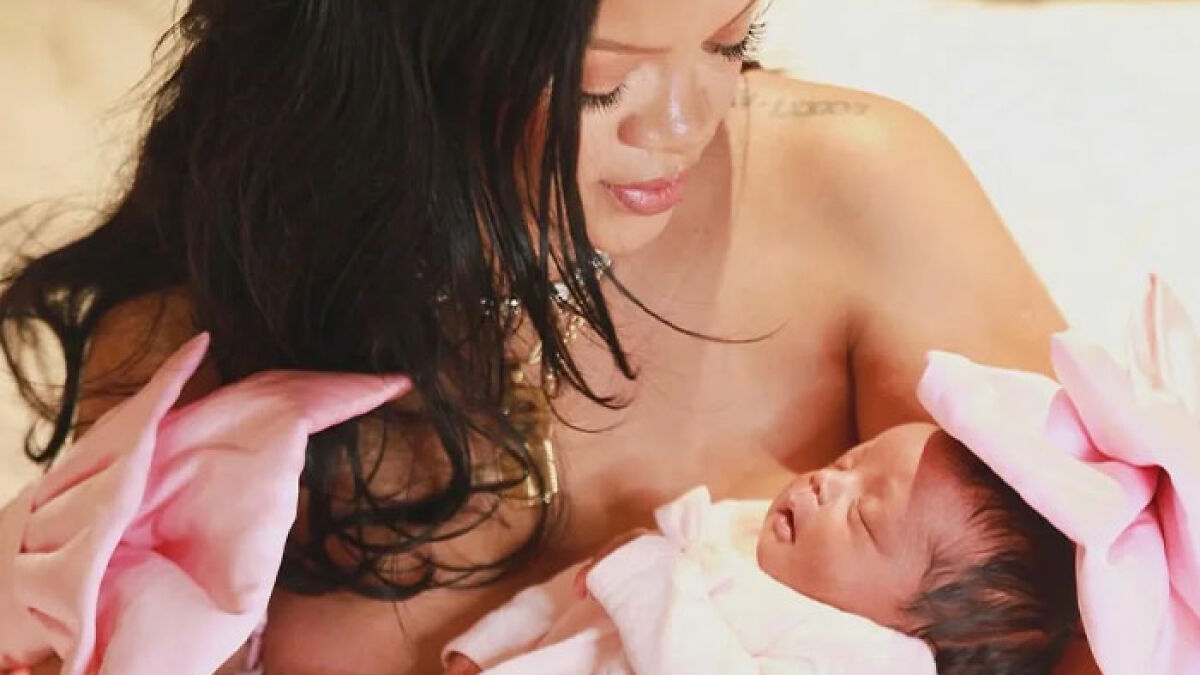 Rihanna holding her newborn daughter wrapped in pink, with fans urging her to change the baby's name due to cruelty concerns