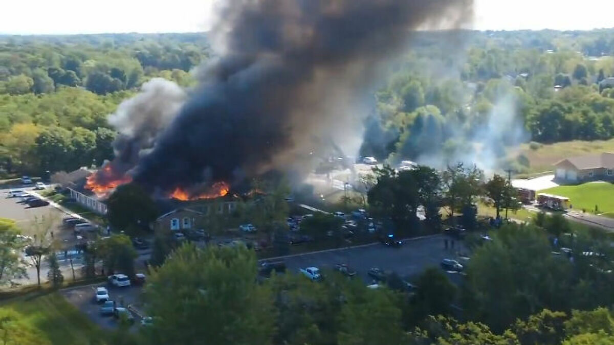 Aerial view of a Michigan church engulfed in flames with thick smoke during the suspect's eerie confession investigation.