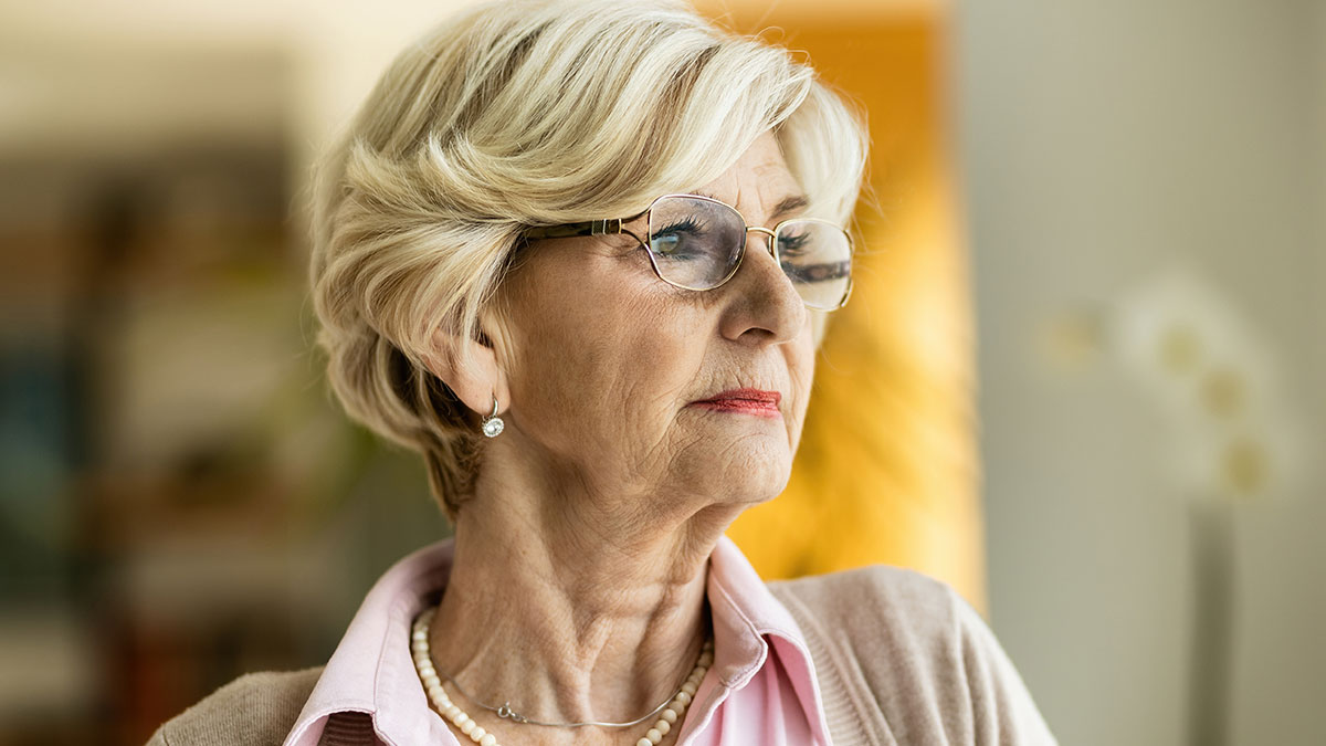 Elderly woman with glasses and pearls looking contemplative indoors, representing crazy things heard from MILs.