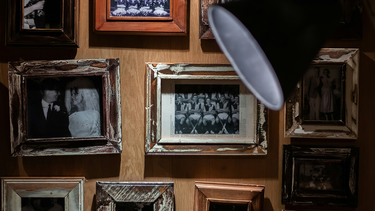 Dimly lit wall with old framed black and white photos creating a creepy atmosphere of unexplained experiences.