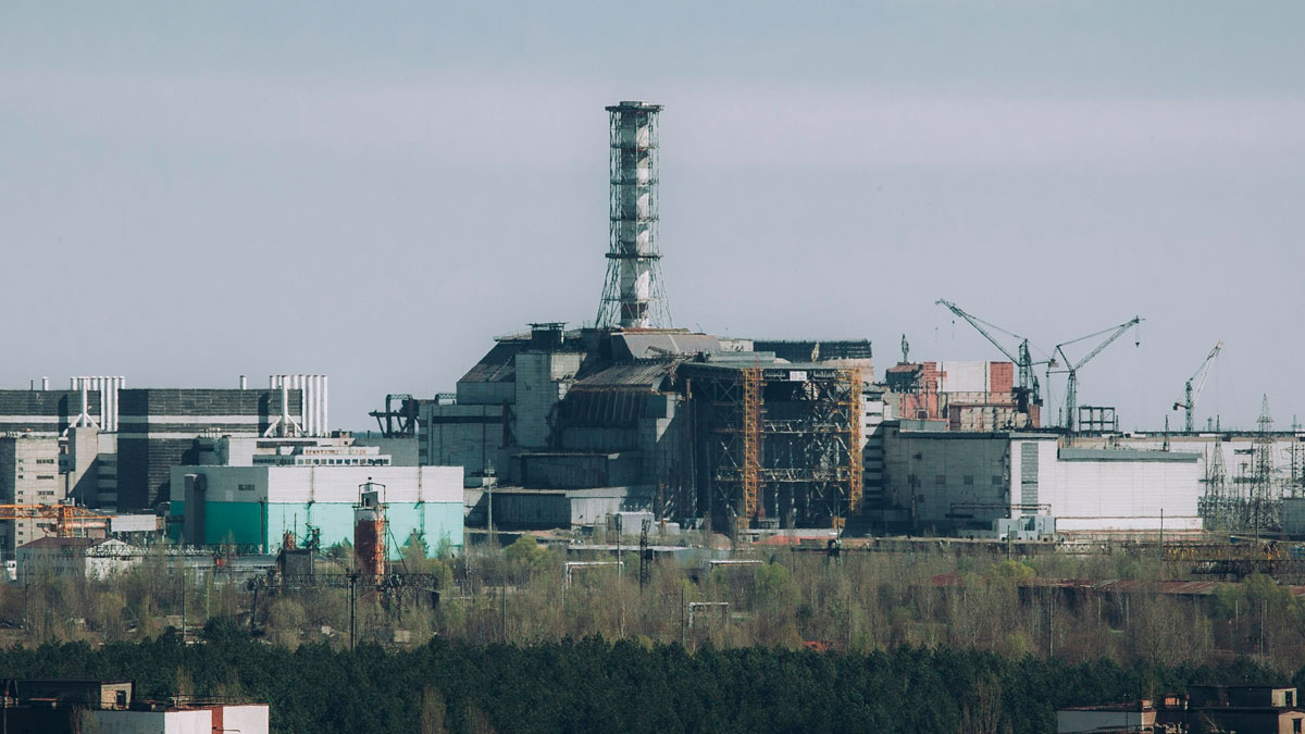 Abandoned industrial complex with rusted structures and overgrown vegetation, showcasing a haunting abandoned place scene.