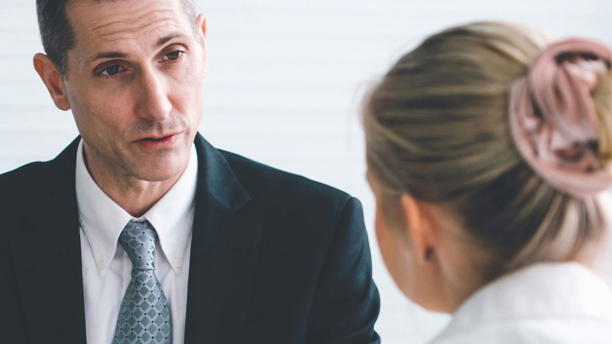 Man in suit talking seriously with woman in an office setting, illustrating a creepy coworker petty response scenario.