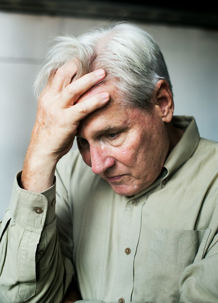 Elderly man appearing worried, holding his head, representing patients who defied medical odds according to doctors.