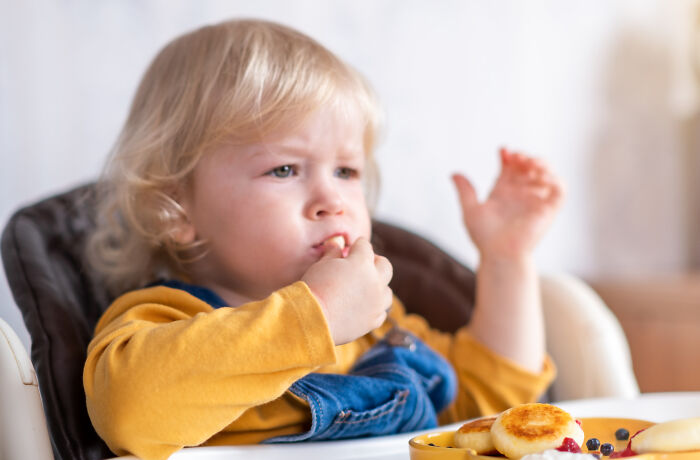 Toddler eating snacks in a high chair, illustrating practical parenting hacks that help save sanity during mealtime.