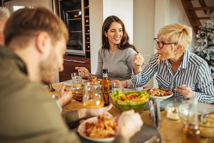 Family dinner scene with people eating pasta, capturing tension after widow snaps at sister&rsquo;s cruel joke about her husband.