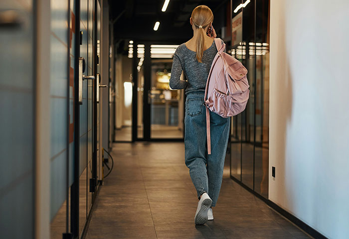Woman with backpack walking down hallway, illustrating poor personal hygiene causing discomfort in close relationships.