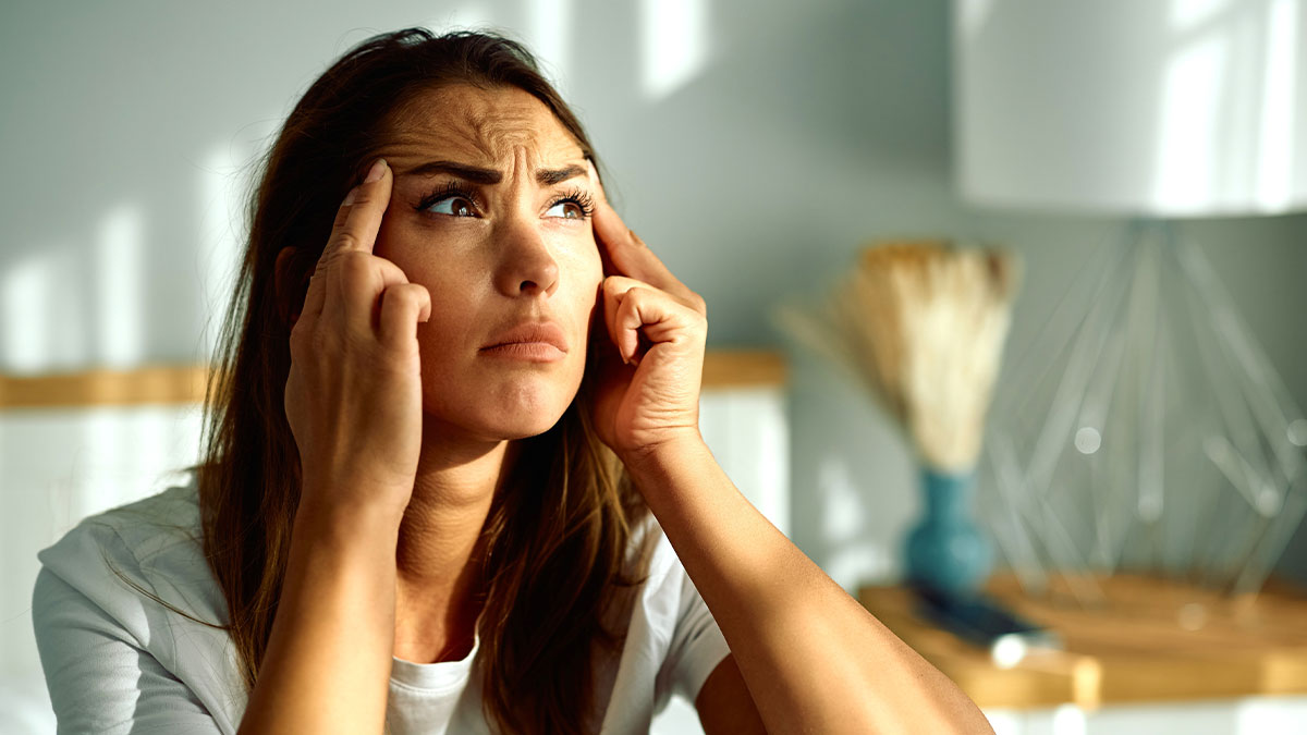 Worried woman touching temples, reflecting tension and conflict about bride banning BFF from bringing baby to wedding.