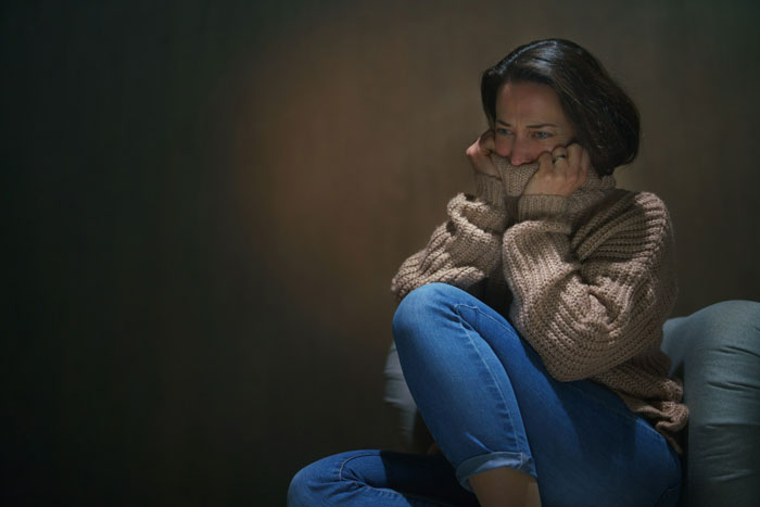 Worried woman sitting alone, wearing a sweater and jeans, reflecting on dog shelter and police involvement situation. Worried woman sitting alone, wearing a sweater and jeans, reflecting on dog shelter and police involvement situation.