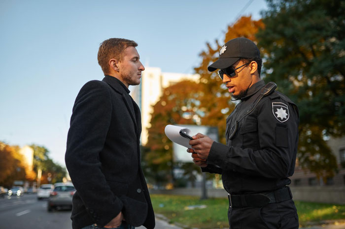 Police officer speaking with a man outdoors as part of a case involving a woman, dog shelter, and adoption dispute Police officer speaking with a man outdoors as part of a case involving a woman, dog shelter, and adoption dispute