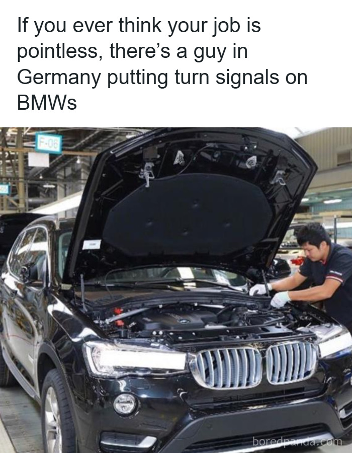 Man working under the hood of a BMW car in a factory, illustrating men humor memes about pointless jobs.