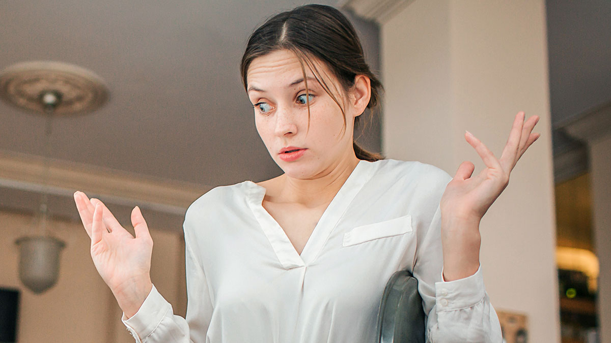Woman in a white shirt looking confused with raised hands, illustrating dumbest customers in the food industry.