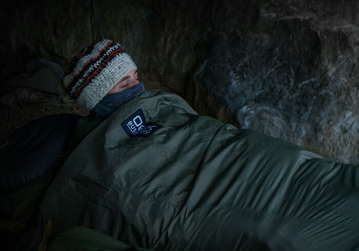 Person wrapped in a sleeping bag inside a dark cave, evoking the eerie atmosphere of creepy stories in the woods. Person wrapped in a sleeping bag inside a dark cave, evoking the eerie atmosphere of creepy stories in the woods.
