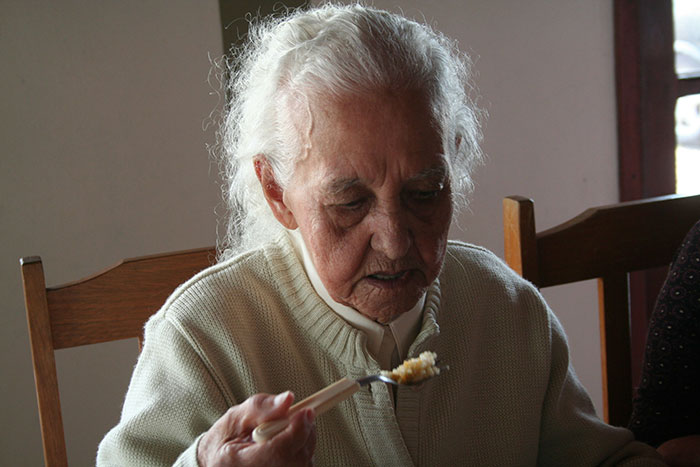 Elderly woman eating at a wooden table, highlighting this food increases dementia risk according to scientists. Elderly woman eating at a wooden table, highlighting this food increases dementia risk according to scientists.