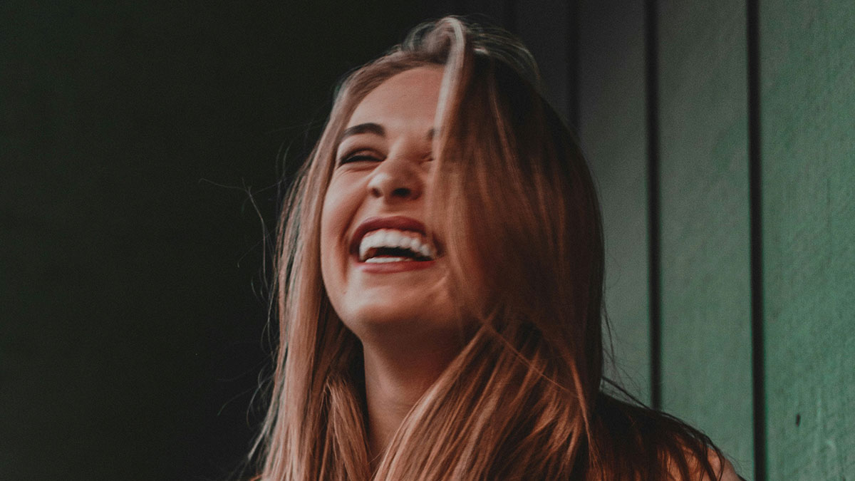 Young woman laughing heartily indoors, capturing the hilariously embarrassing moments from doctoru2019s appointments.