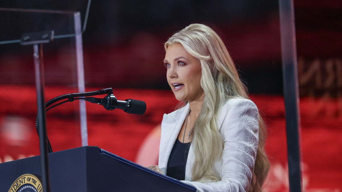 Erika Kirk speaking at a podium with microphone, sharing thoughts on forgiveness after her husbandu2019s assassination.