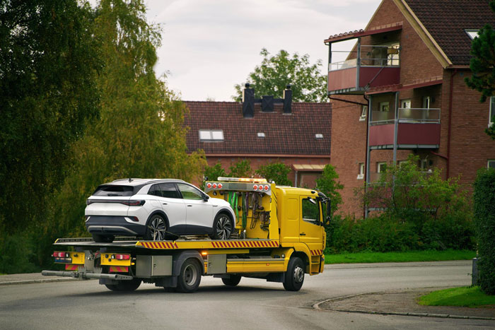Tow truck carrying a white SUV on a residential street, illustrating a police warning over driveway disputes and entitlement. Tow truck carrying a white SUV on a residential street, illustrating a police warning over driveway disputes and entitlement.