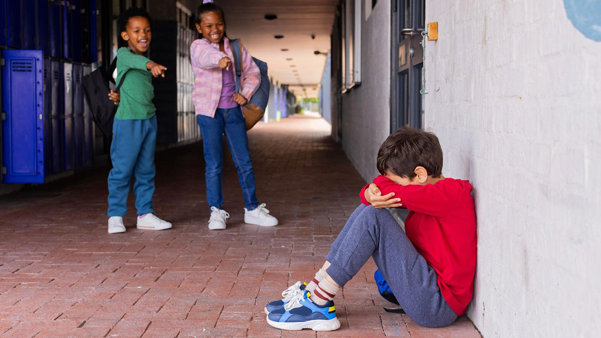 Three kids laughing and pointing at a boy sitting alone, capturing mind-boggling conversations about how adults survive.