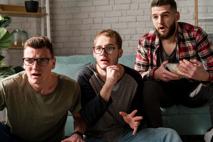 Three men sitting on a couch looking shocked and surprised, reacting to a family conflict involving a rude hubby. Three men sitting on a couch looking shocked and surprised, reacting to a family conflict involving a rude hubby.