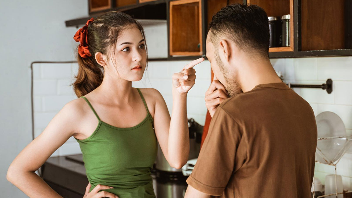 Woman stands up for cousin's wife confronting rude husband in kitchen setting during heated family argument.