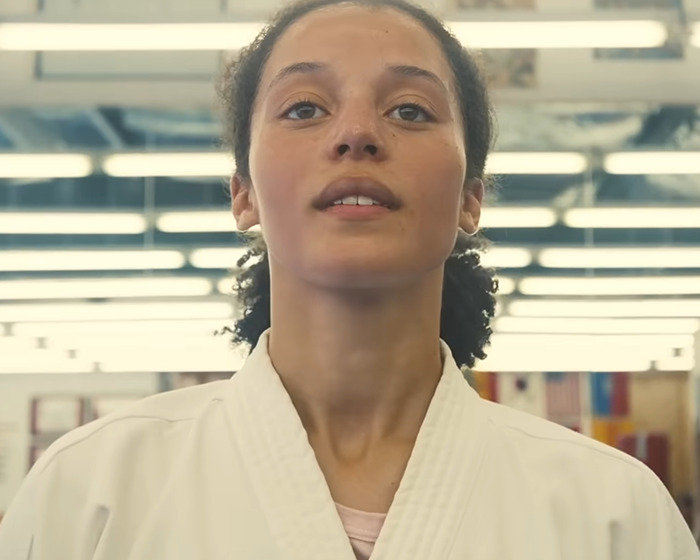 Young woman in a martial arts uniform standing confidently indoors, fans praise Chase Infiniti response to reporter question. Young woman in a martial arts uniform standing confidently indoors, fans praise Chase Infiniti response to reporter question.