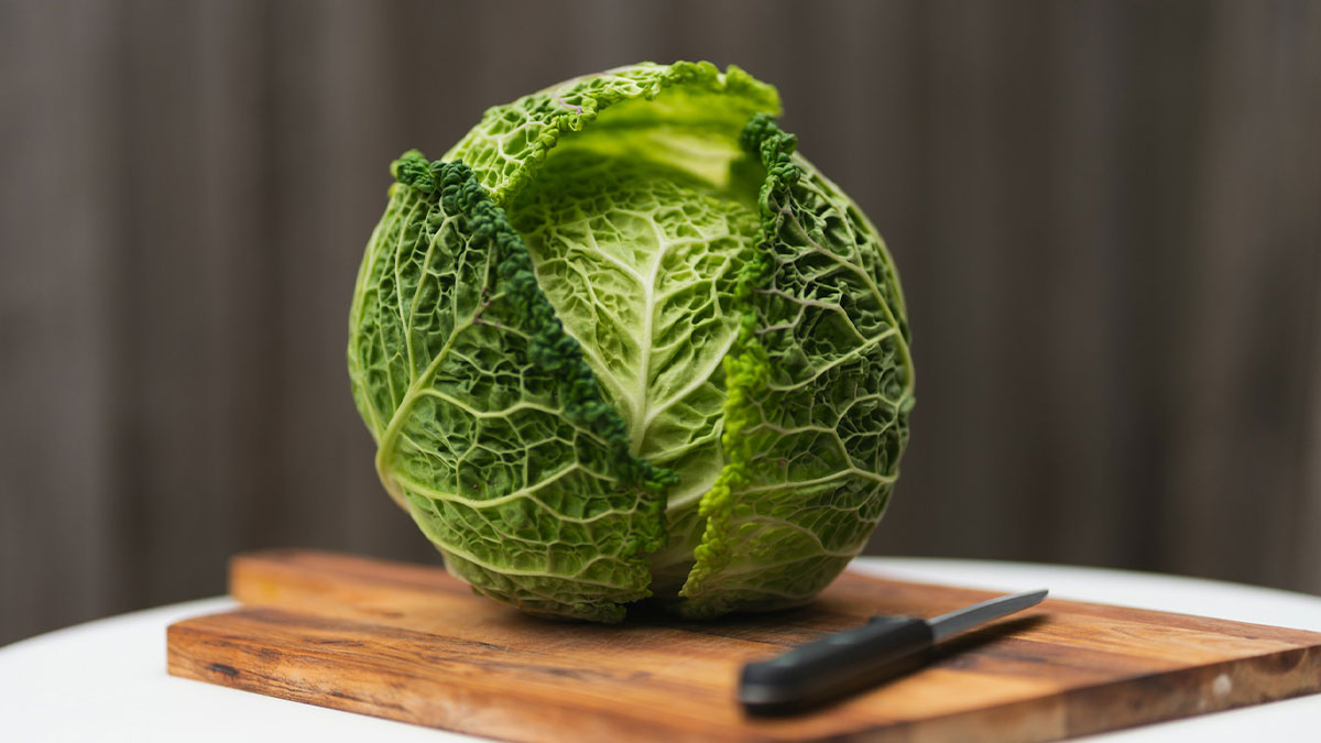 Green cabbage on a wooden cutting board with a knife, illustrating quick ways people have seen someone get fired.