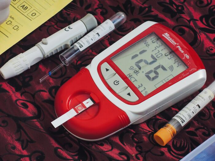 Glucose meter and lancets on patterned cloth displaying medical tools used for patients defying medical odds.