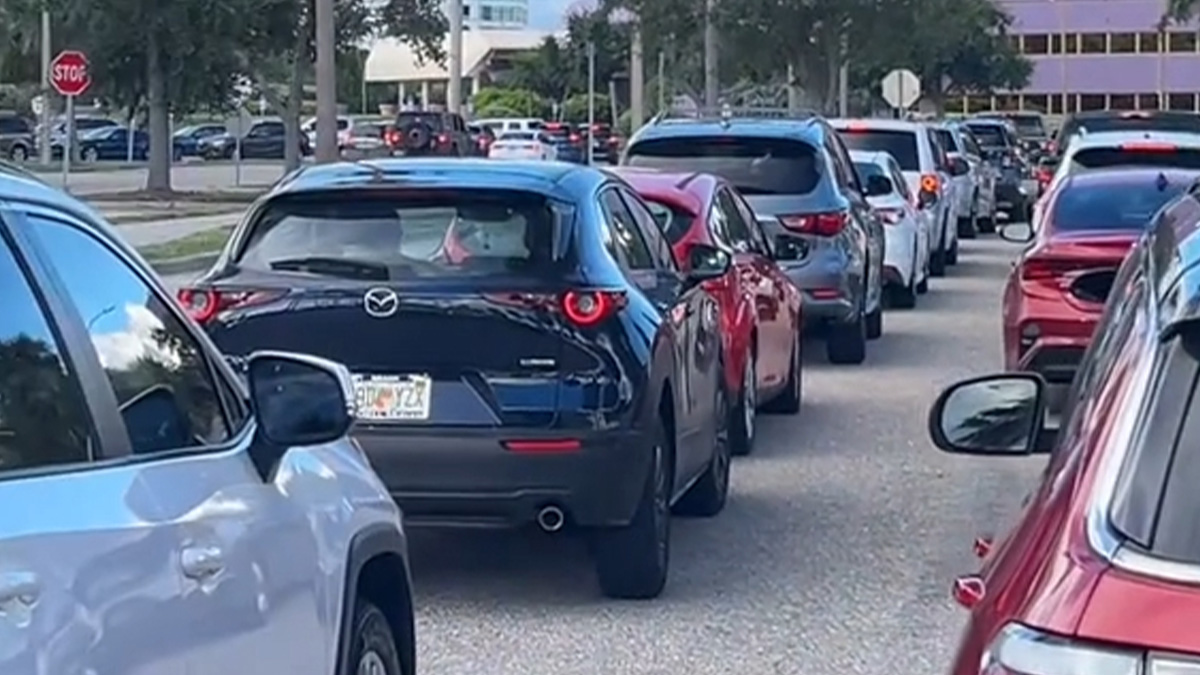 Long line of cars waiting outside food bank, illustrating USA richest poor people visiting for aid.