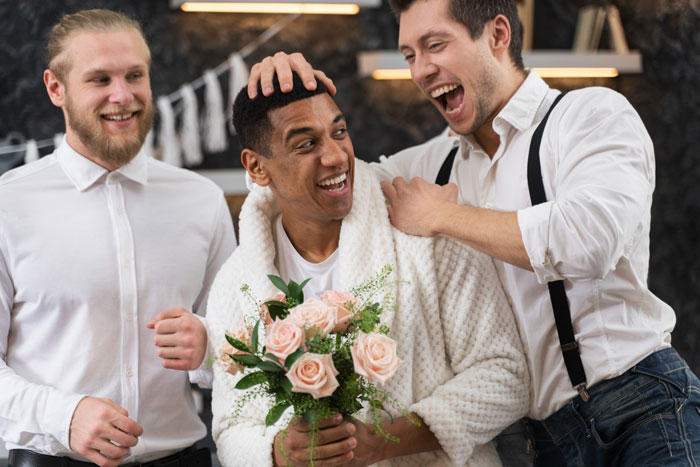 Groom laughing with best friends at bachelor party, holding bouquet, while celebrating before wedding day event. Groom laughing with best friends at bachelor party, holding bouquet, while celebrating before wedding day event.