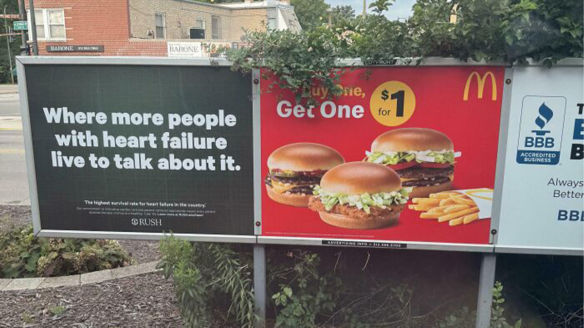 Billboard showing advertising placement fail with a heart failure health message next to a fast food promotion.