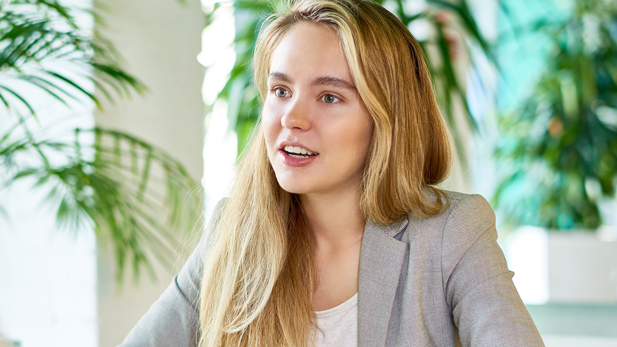 Young woman speaking her truth in a bright office with plants, capturing a moment that won the internet attention.