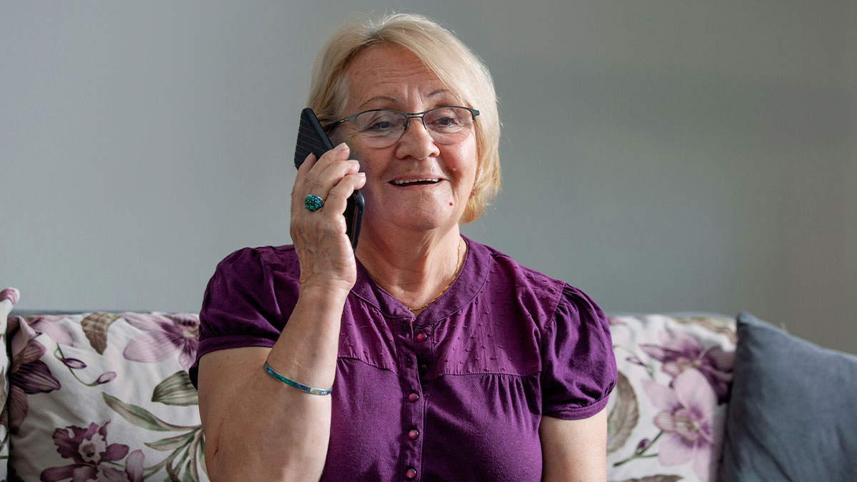 Older woman struggling with technology, holding a smartphone to her ear, illustrating cluelessness with technology in seniors.