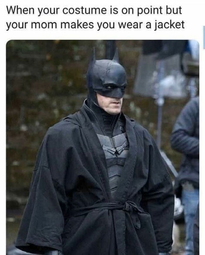 Batman in a detailed costume wearing an oversized black jacket, humorously highlighting super culture entertaining memes.