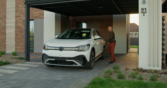 Man standing near white car blocking driveway, illustrating neighbor towing situation and entitlement conflict. Man standing near white car blocking driveway, illustrating neighbor towing situation and entitlement conflict.