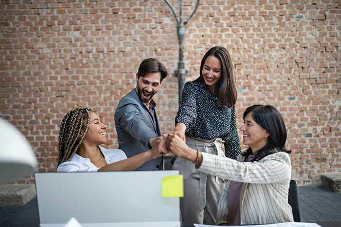 Four coworkers in a casual office setting joining hands, representing a confrontation about a married coworker and divorce fears. Four coworkers in a casual office setting joining hands, representing a confrontation about a married coworker and divorce fears.