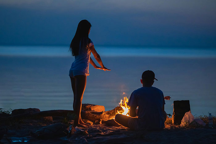 Couple by a campfire at night with man considering woman his girlfriend after one date and giving anniversary gift. Couple by a campfire at night with man considering woman his girlfriend after one date and giving anniversary gift.