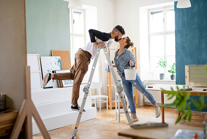 Couple sharing a kiss while painting their home, hinting at a guy convinced he took an art class with his girlfriend. Couple sharing a kiss while painting their home, hinting at a guy convinced he took an art class with his girlfriend.