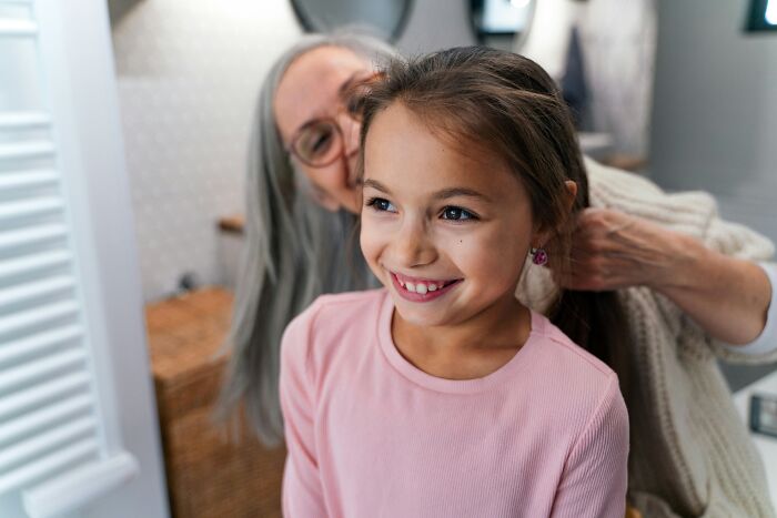 Grandmother using parenting hacks to braid young girl's hair, sharing moments that save sanity and create joy at home.