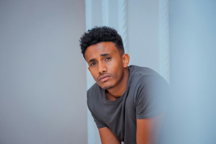 Young man in a gray shirt looking thoughtful, illustrating subtle ways misogyny can creep into daily lives.