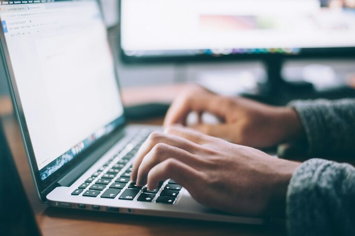 Close-up of adult hands typing on a laptop keyboard, illustrating adults who failed to understand growing up.